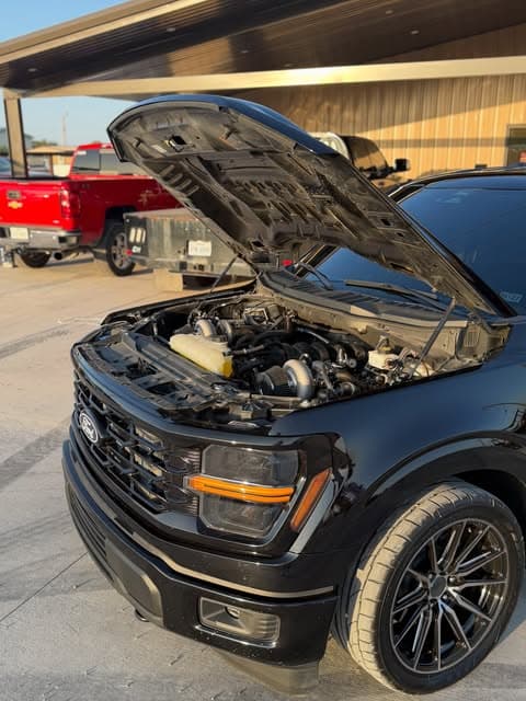 Black truck in the shop with its hood open