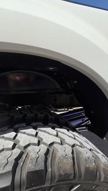 Close view of a lifted truck's wheel, tire, and suspension