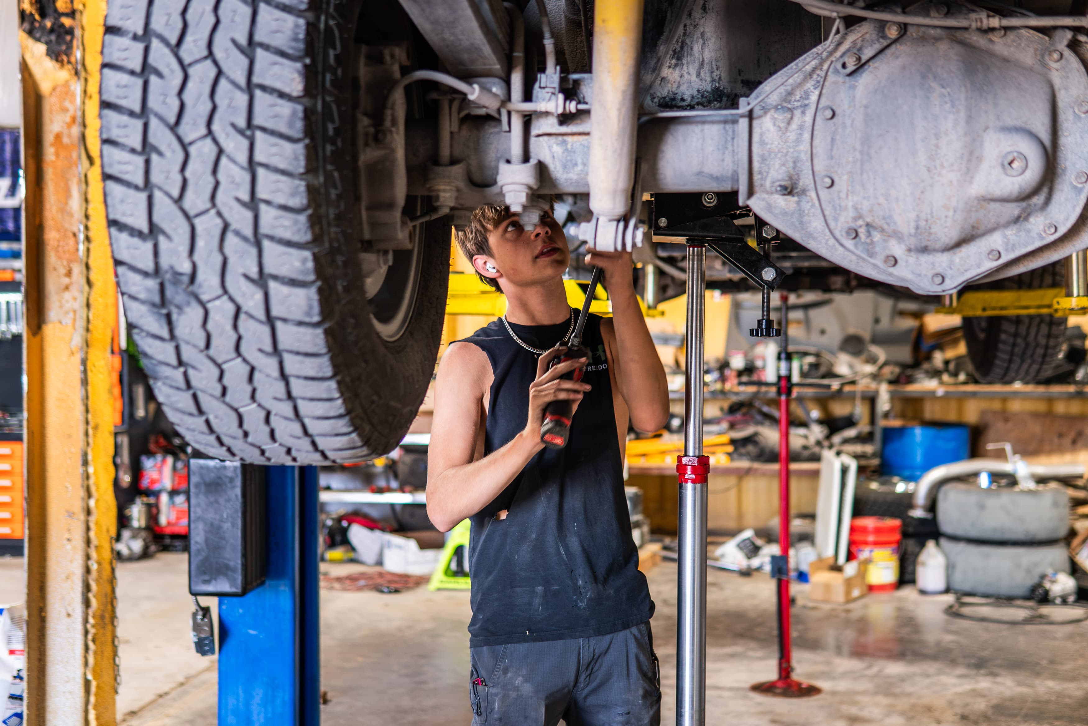 Technician working beneath the drivetrain of a heavy-duty truck